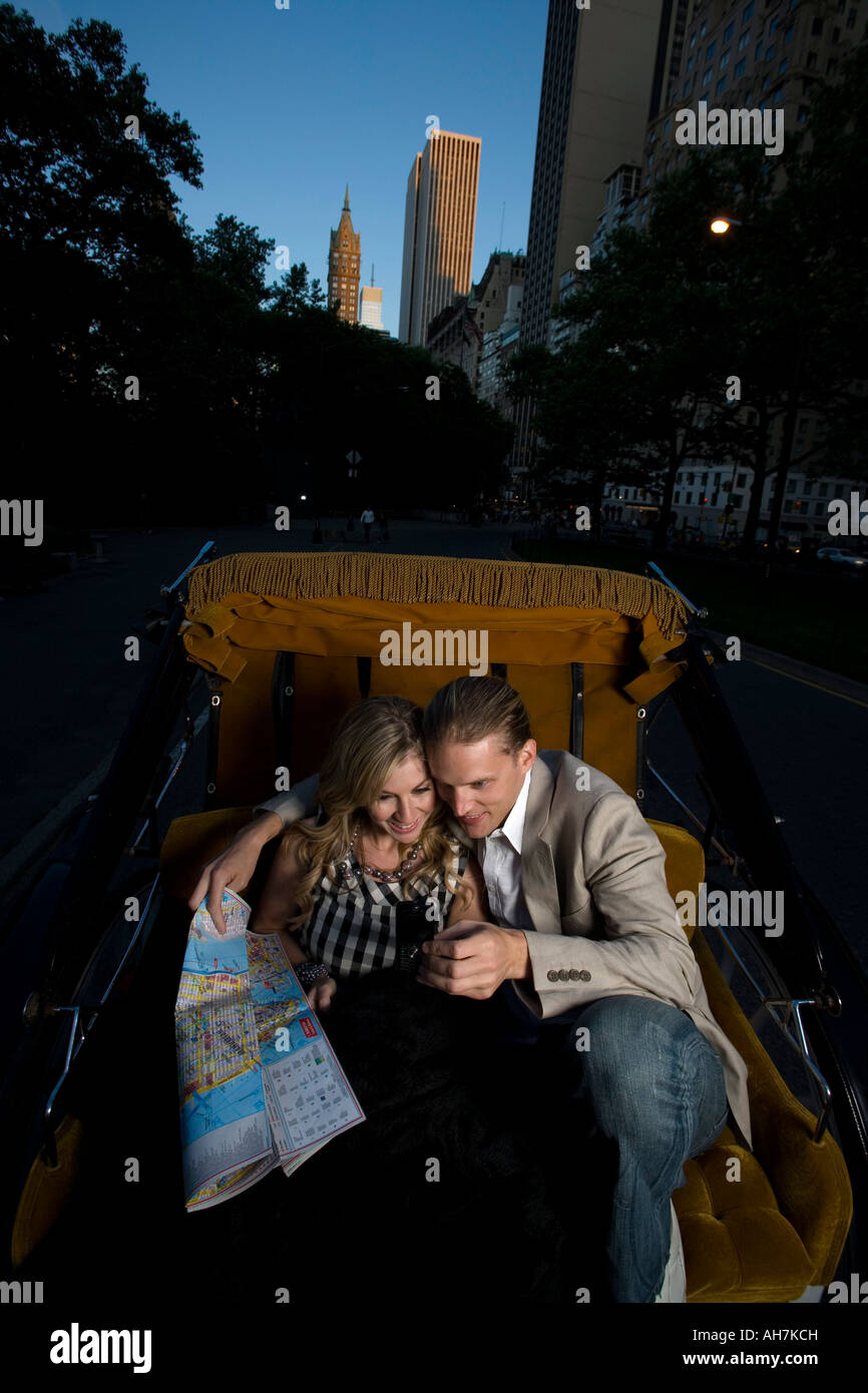 Coppia giovane di equitazione in un carrello horsedrawn e tenendo una road map, Central Park, Manhattan, New York, New York, Stati Uniti d'America Foto Stock