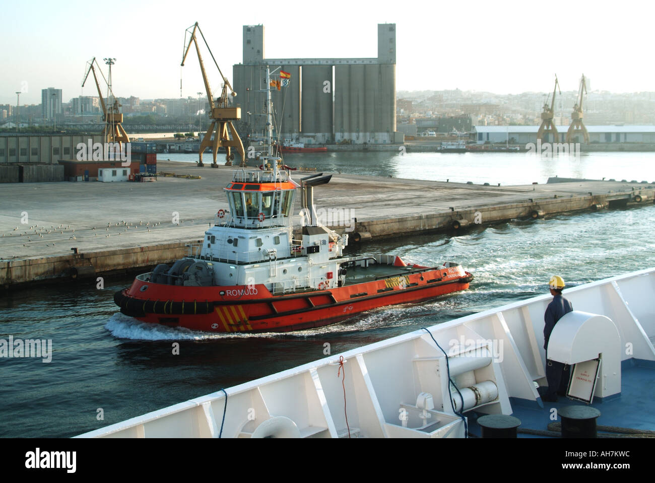 Installazioni portuali di Tarragona con rimorchiatore Romulo in transito passando per la nave da crociera che entra nel porto membro dell'equipaggio guardando sulla spagna Foto Stock