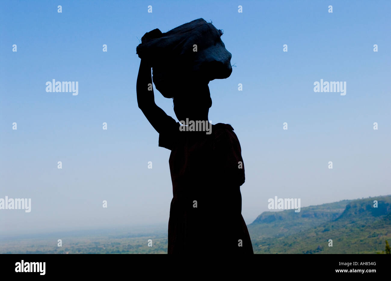 Silhouette di donna trasporta un carico in Africa rurale Foto Stock