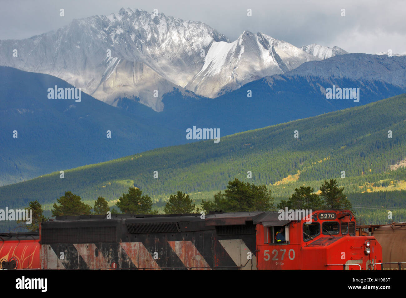 Il Canadian National Railway treno merci nei pressi della stazione ferroviaria di Jasper con montagne rocciose in background. Foto Stock