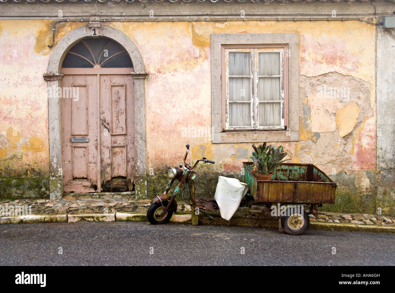 Sintra, Portogallo. Vecchia motocicletta con rimorchio trasporto di un grande impianto di cactus, parcheggiato al di fuori di una vecchia casa portoghese con peeling paint Foto Stock