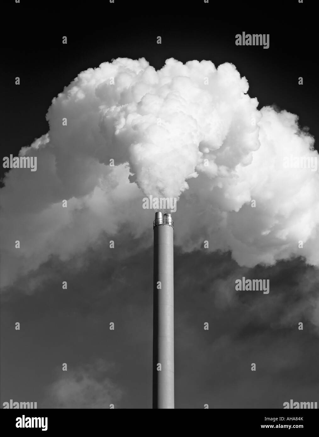Regno Unito. Una fabbrica di camino di emissione di un enorme pennacchio di fumo bianco contro un cielo scuro, monocromatico Foto Stock