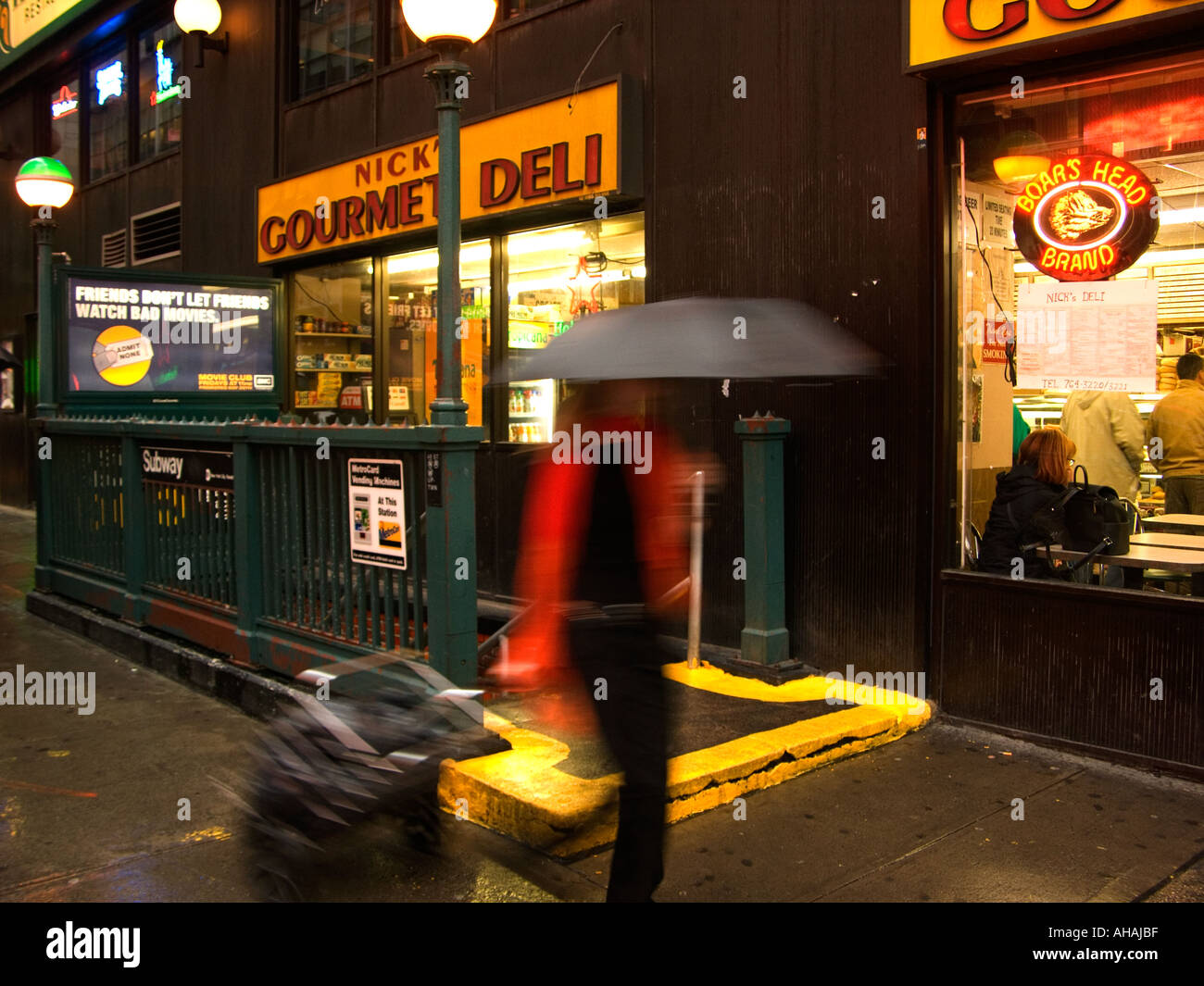 La donna con la valigia su ruote a piedi passato new york deli finestra la notte Foto Stock