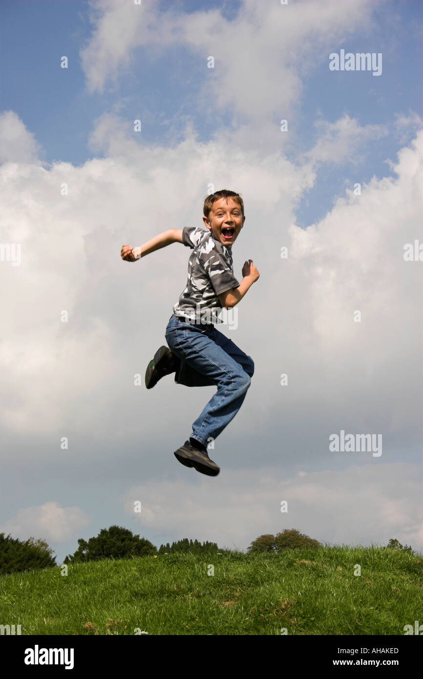 Dieci anni di old boy jumping ruotando ed estraendo un sorpreso di fronte. Foto Stock