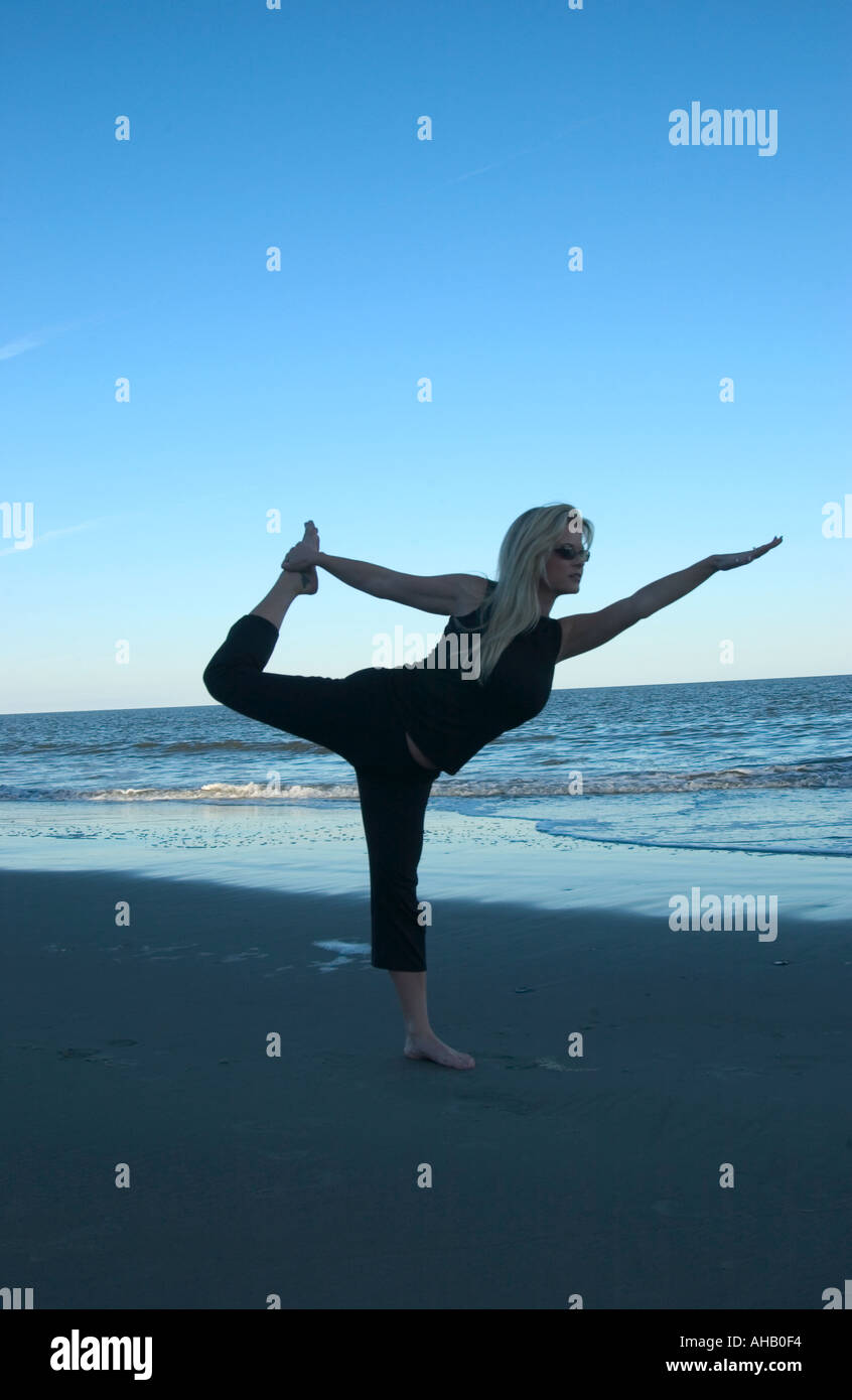 Giovane donna le pratiche yoga esercizi sulla spiaggia USA Foto Stock