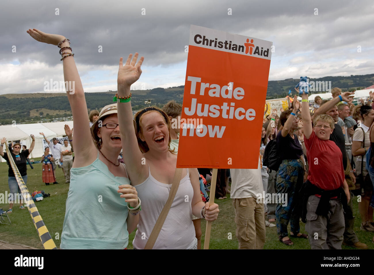 Due giovani donne wave Christian Aid giustizia commerciale ora cartelloni a fare la storia di povertà dimostrazione Greenbelt 2005 REGNO UNITO Foto Stock