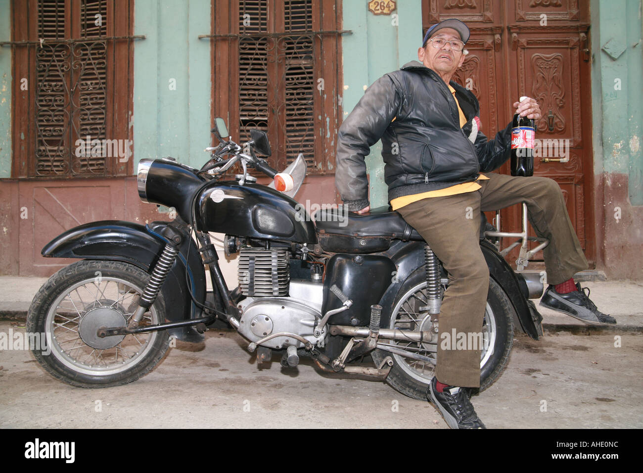 Cuba Havana un uomo anziano sulla sua motocicletta vintage tenendo una bottiglia con coke nazionale tu cola Foto Stock