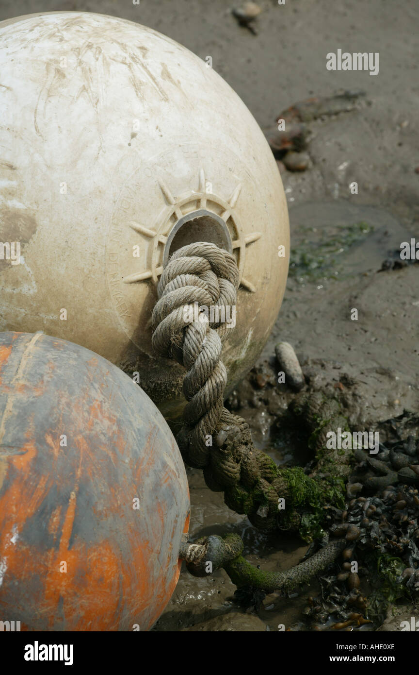 Due bianchi bouy che mostra a bassa marea con attacco funi visibile nella banca del fiume fango incentrato sulla forte tradizione fissare la fune Foto Stock