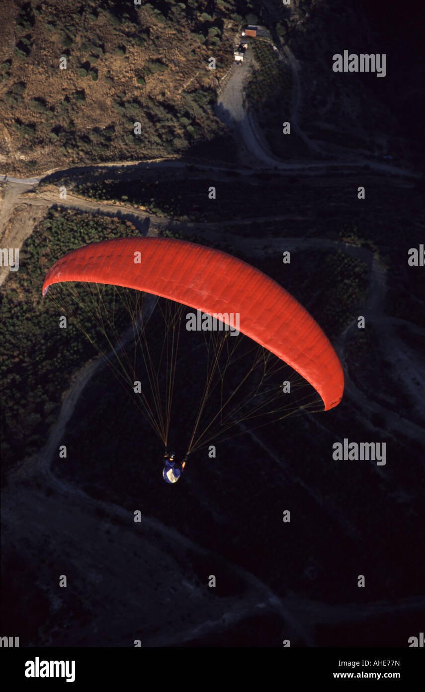 Pilota di parapendio volando sopra la strada nelle montagne del nord di Cipro Foto Stock