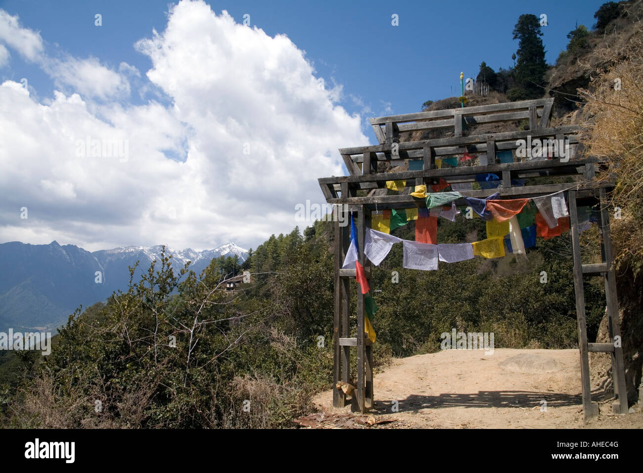 Cime innevate in legno arco di ingresso e bandiere di preghiera Taktshang Goemba Bhutan Foto Stock