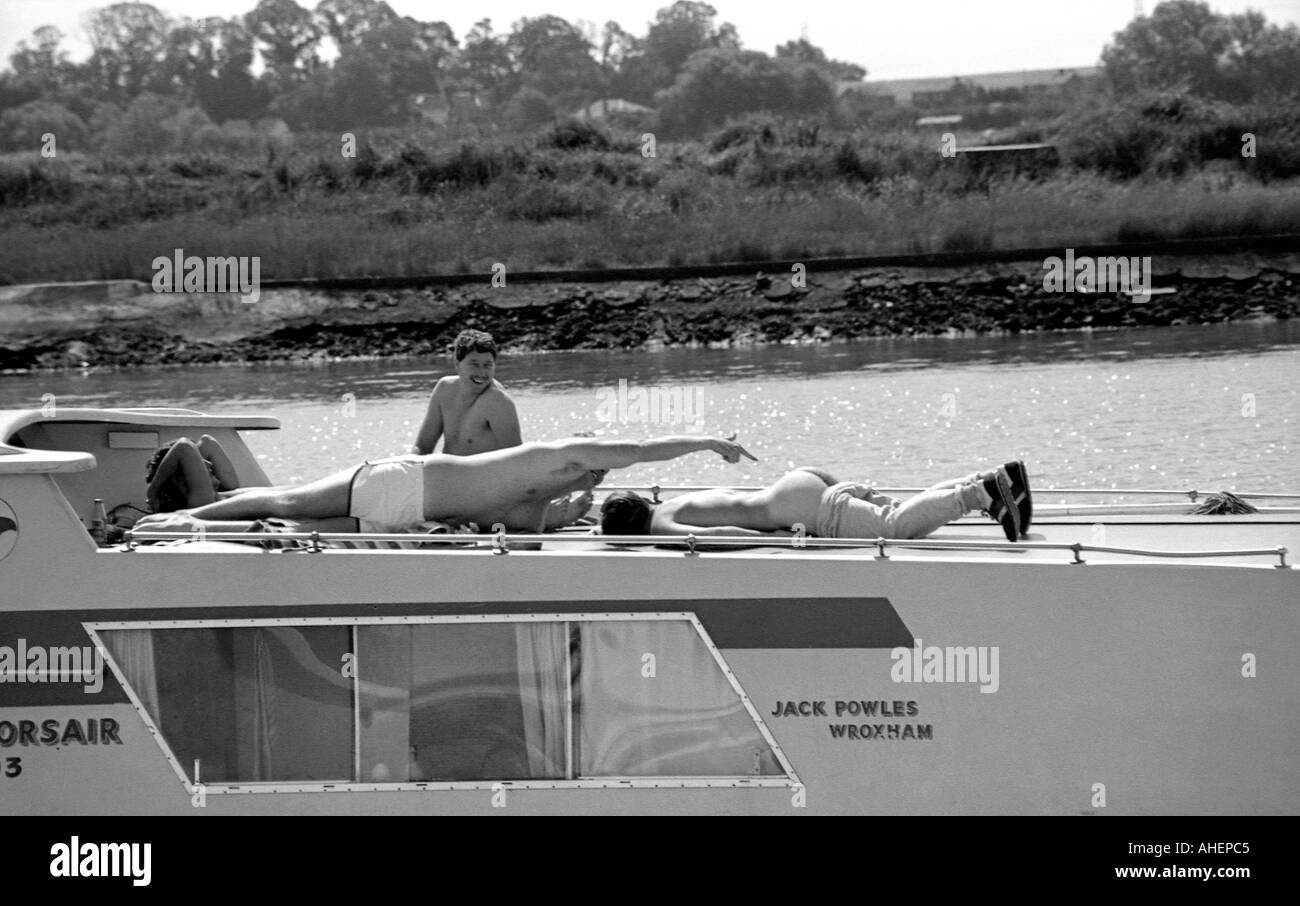 Un gruppo di giovani uomini su una barca di piacere sulle rive di un fiume divertendosi Foto Stock