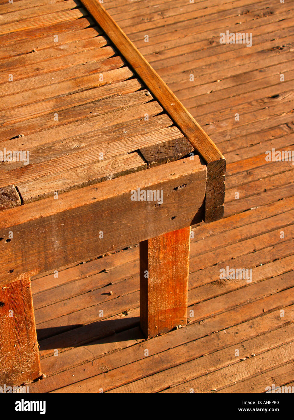 Lunga panca di legno che si elevano da una lunga planked pavimento in legno nel pomeriggio, mostra ombre lunghe Foto Stock