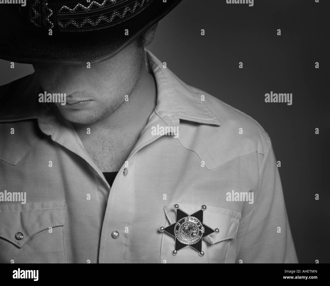 Cowboy guardando verso il basso sotto il cappello con lo sceriffo del badge  sulla camicia Foto stock - Alamy