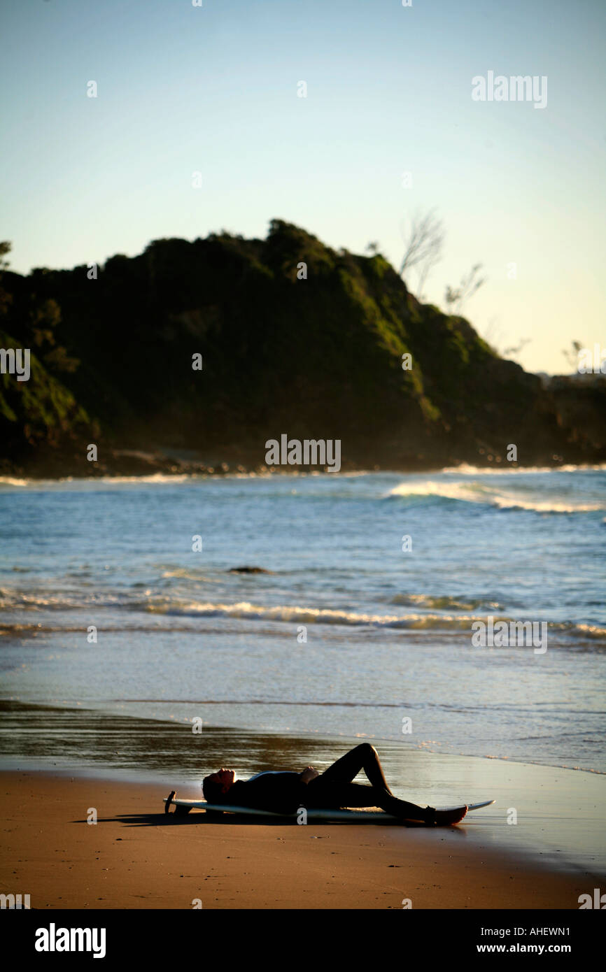 Una giovane donna si rilassa dopo la navigazione a Wategos Beach Byron Bay Australia Foto Stock