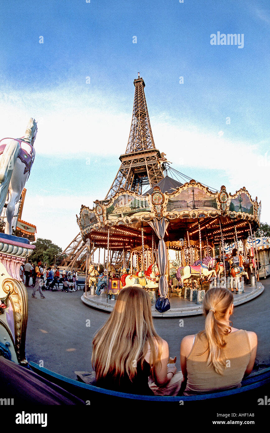 Parigi Francia, Vista della Torre Eiffel con Merry Go Round, antica giostra e turisti femmina seduti da dietro Foto Stock