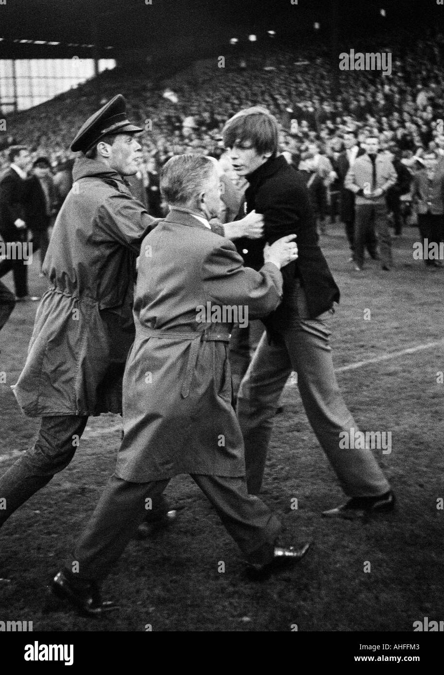 Calcio, Bundesliga, 1965/1966, FC Schalke 04 contro Hamburger SV 2:1, Glueckaufkampfbahn Stadium di Gelsenkirchen, i tifosi di calcio sul passo, palpability, violenza, due custodi tenta di rimuovere un giovane tifoso di calcio Foto Stock