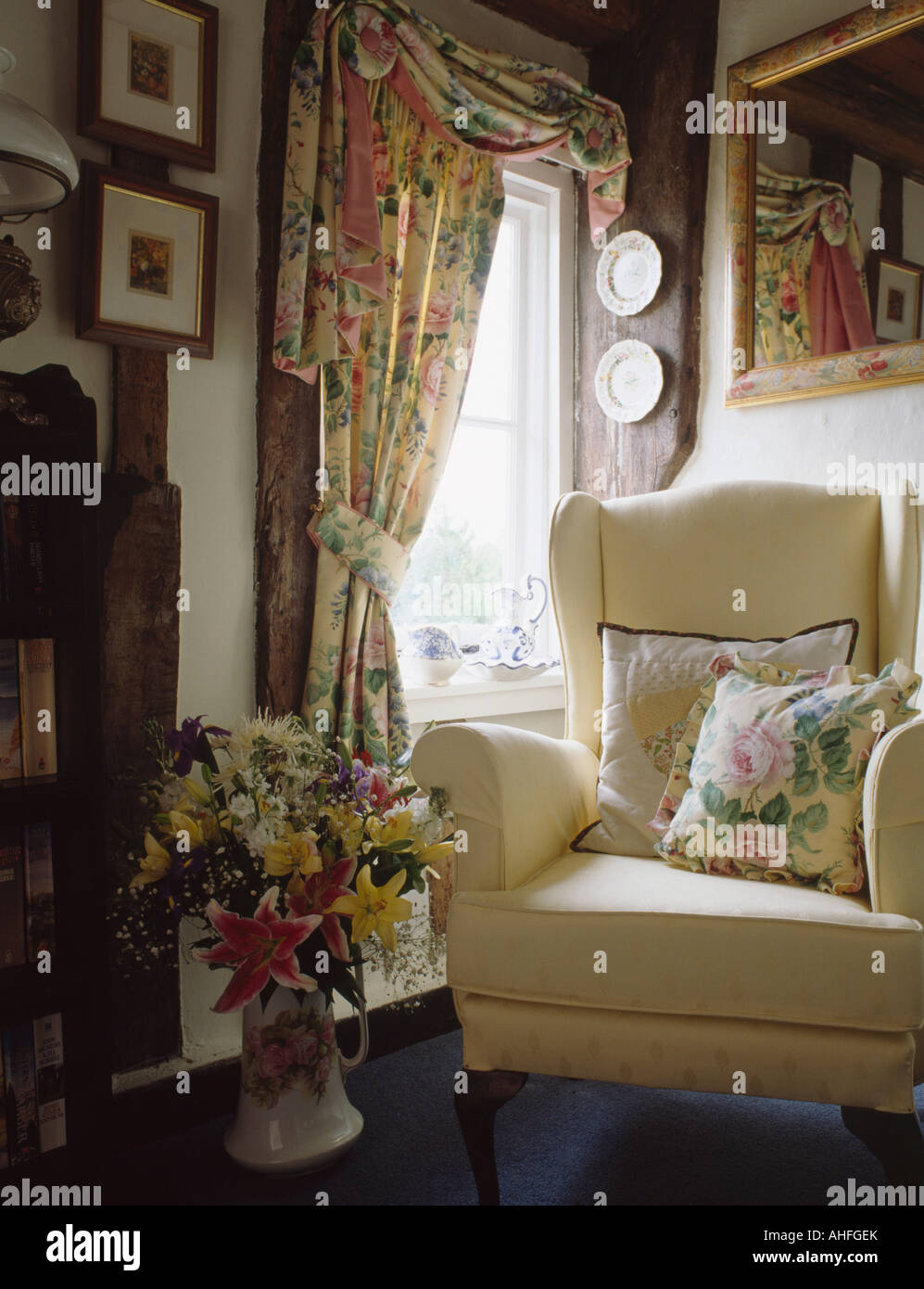 Tendaggi floreali e corrispondenza di cuscino sulla poltrona di crema in cottage soggiorno Foto Stock