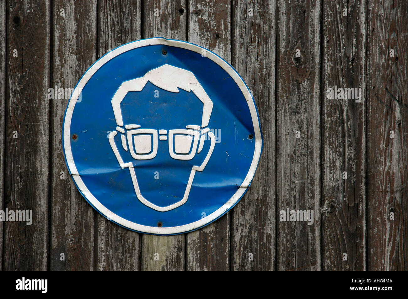 Ammaccato cartello blu sulla porta di legno, occhiali di protezione necessario Foto Stock