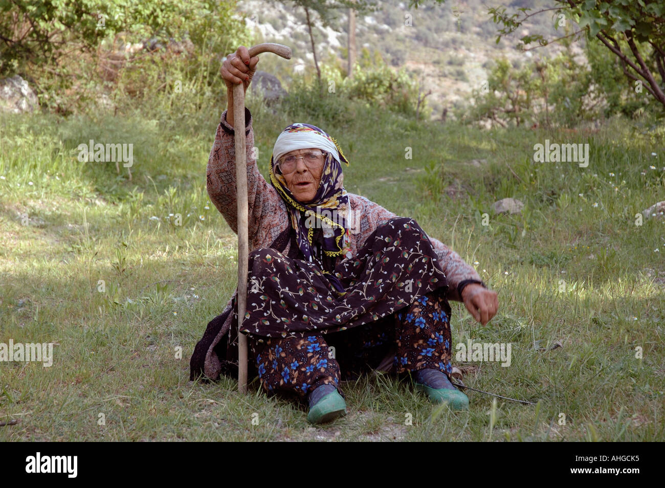 Donna seduta in erba sul ciglio della strada tendente al pascolo e la sua capra nel sud della Turchia villaggio hilltown.nomadic Foto Stock