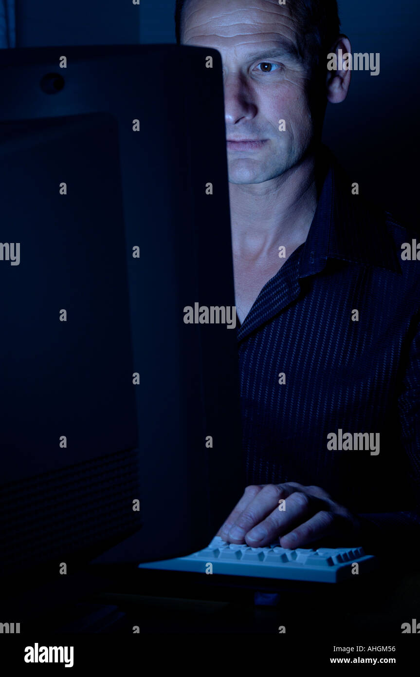 Uomo al lavoro in ritardo a un computer Foto Stock