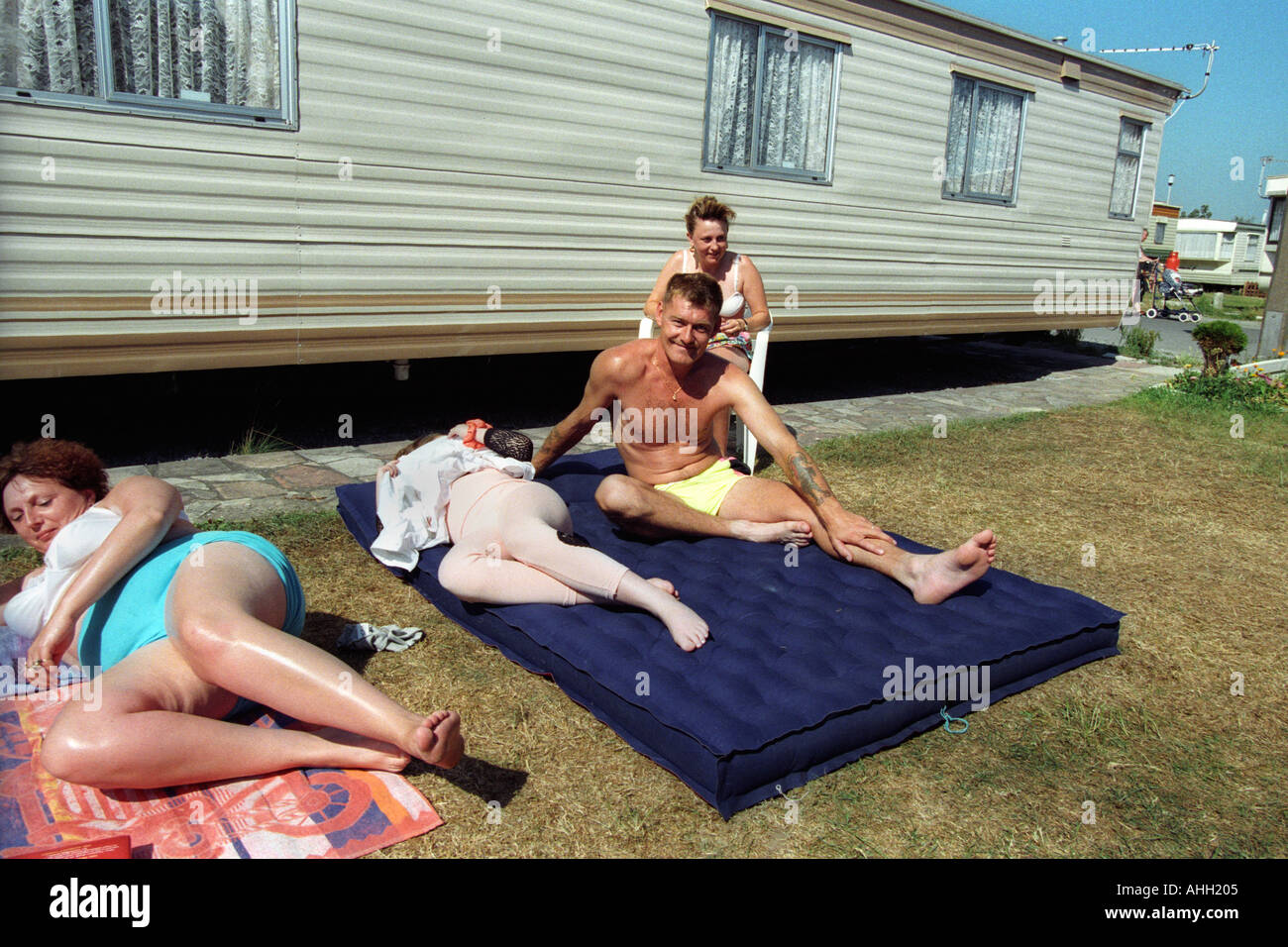 Gruppo familiare di relax al sole al di fuori della loro roulotte statiche a Trecco Bay Porthcawl South Wales UK Foto Stock