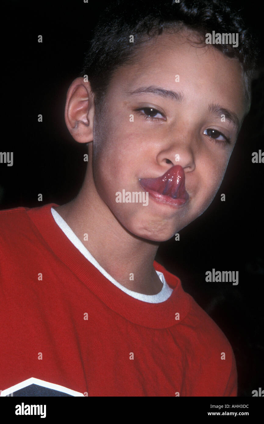 Ragazzo di toccare il suo naso con la sua lingua Foto Stock