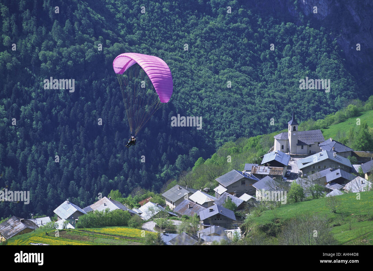 Un parapendio vola sopra un villaggio savoiardo savoie sulle alpi francesi francia Foto Stock
