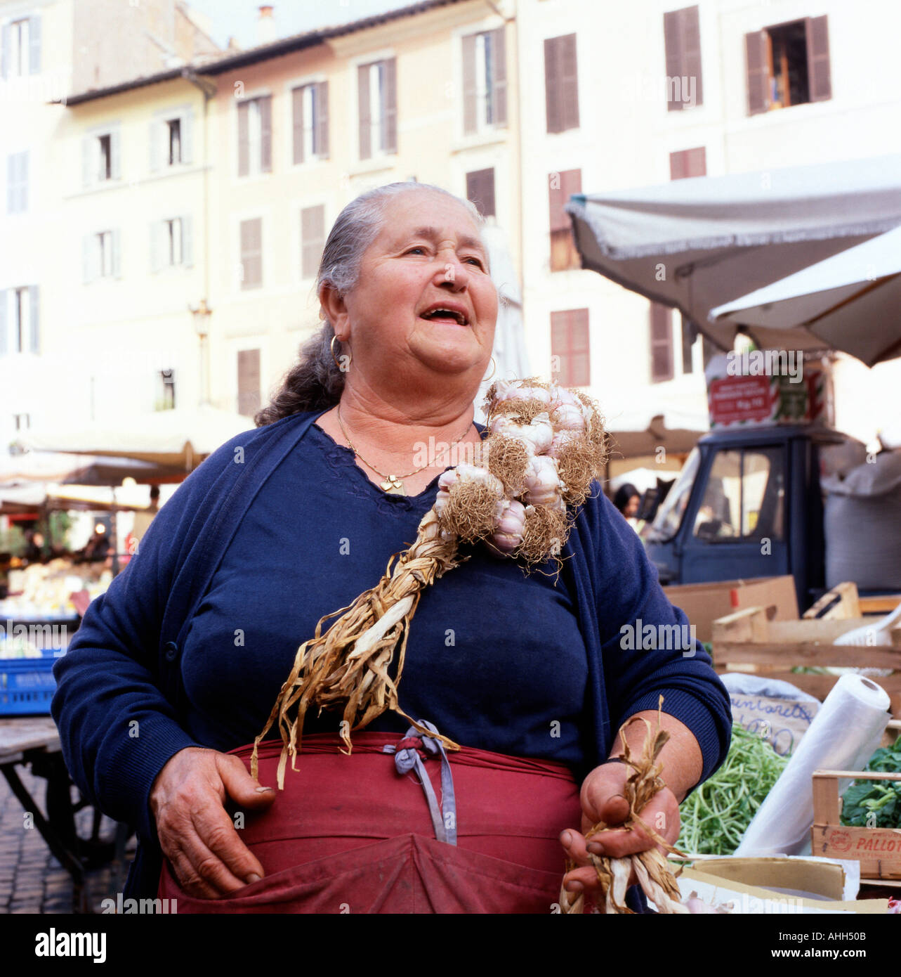 Una donna anziana commerciante di mercato femminile che vende i bulbi di aglio delle trecce In corda in campo de Fiori frutta e veg strada Mercato alimentare Roma Italia KATHY DEWITT Foto Stock