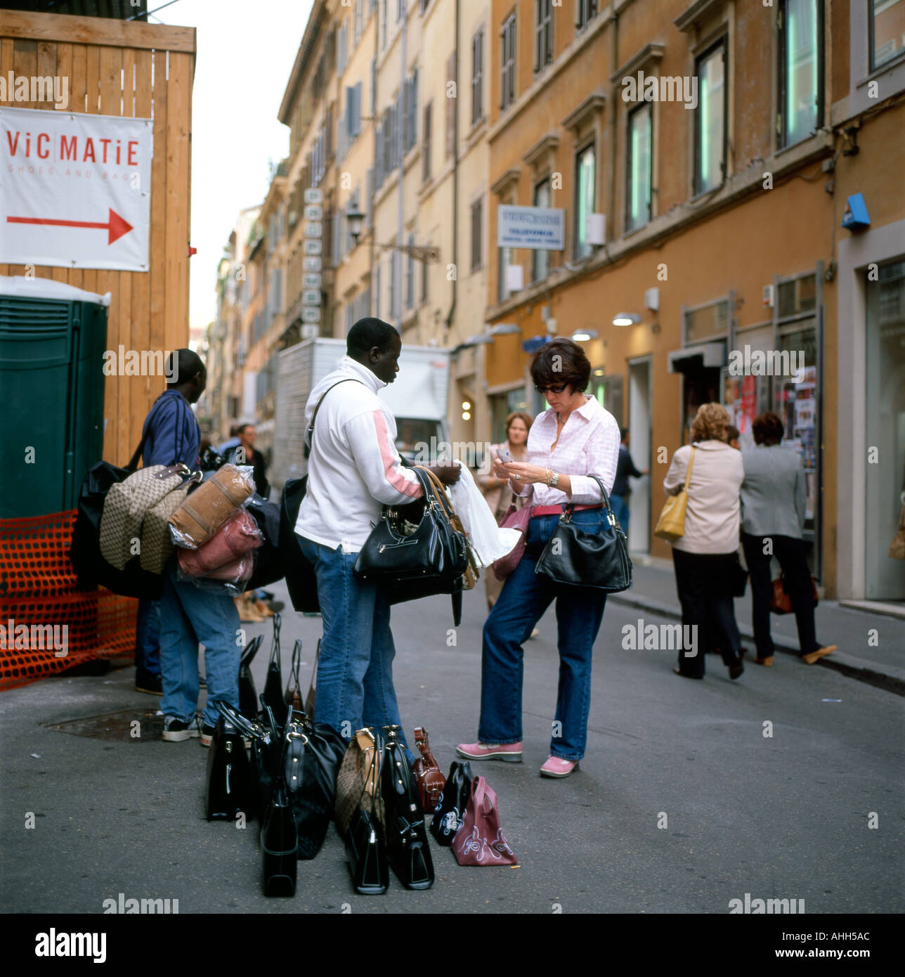 Una donna americana tourist acquisto di un designer borsetta da un africano street venditore a Roma Italia KATHY DEWITT Foto Stock