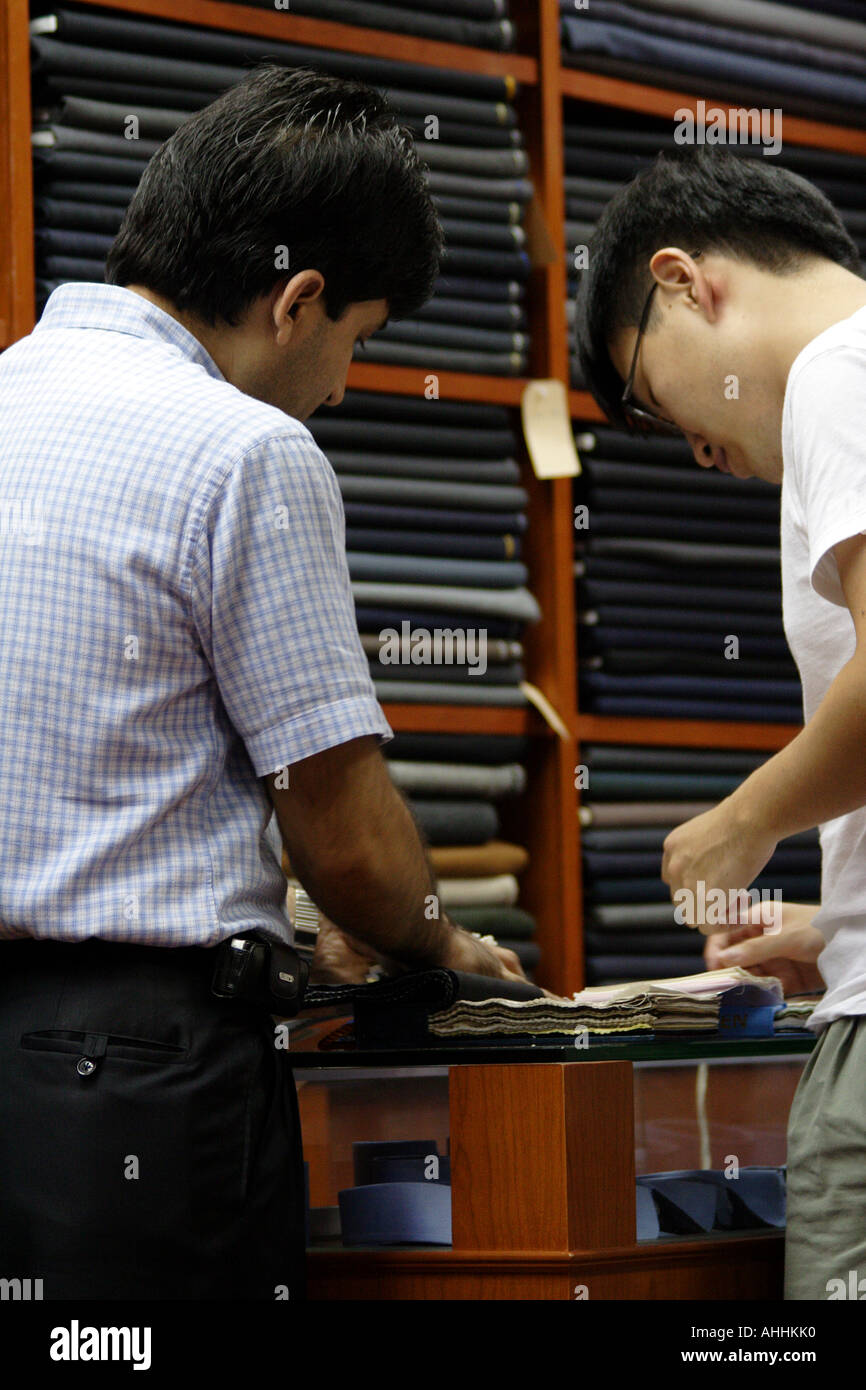 Hong Kong sarto e un cliente a raccogliere materiale di fronte Reems della tuta tessuto Foto Stock