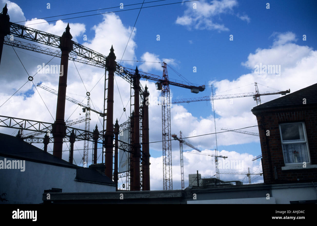 Casa e gasometro nella zona portuale della città con un certo numero di grandi gru di costruzione dietro. Dublino, Repubblica d'Irlanda. Foto Stock