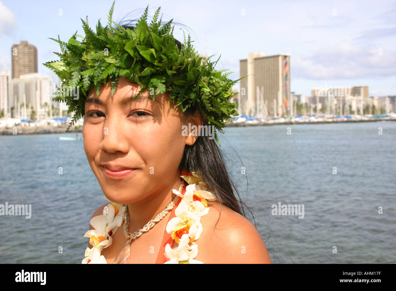 Giovane donna Hawaiana con haku lei e Waikiki in background Foto Stock