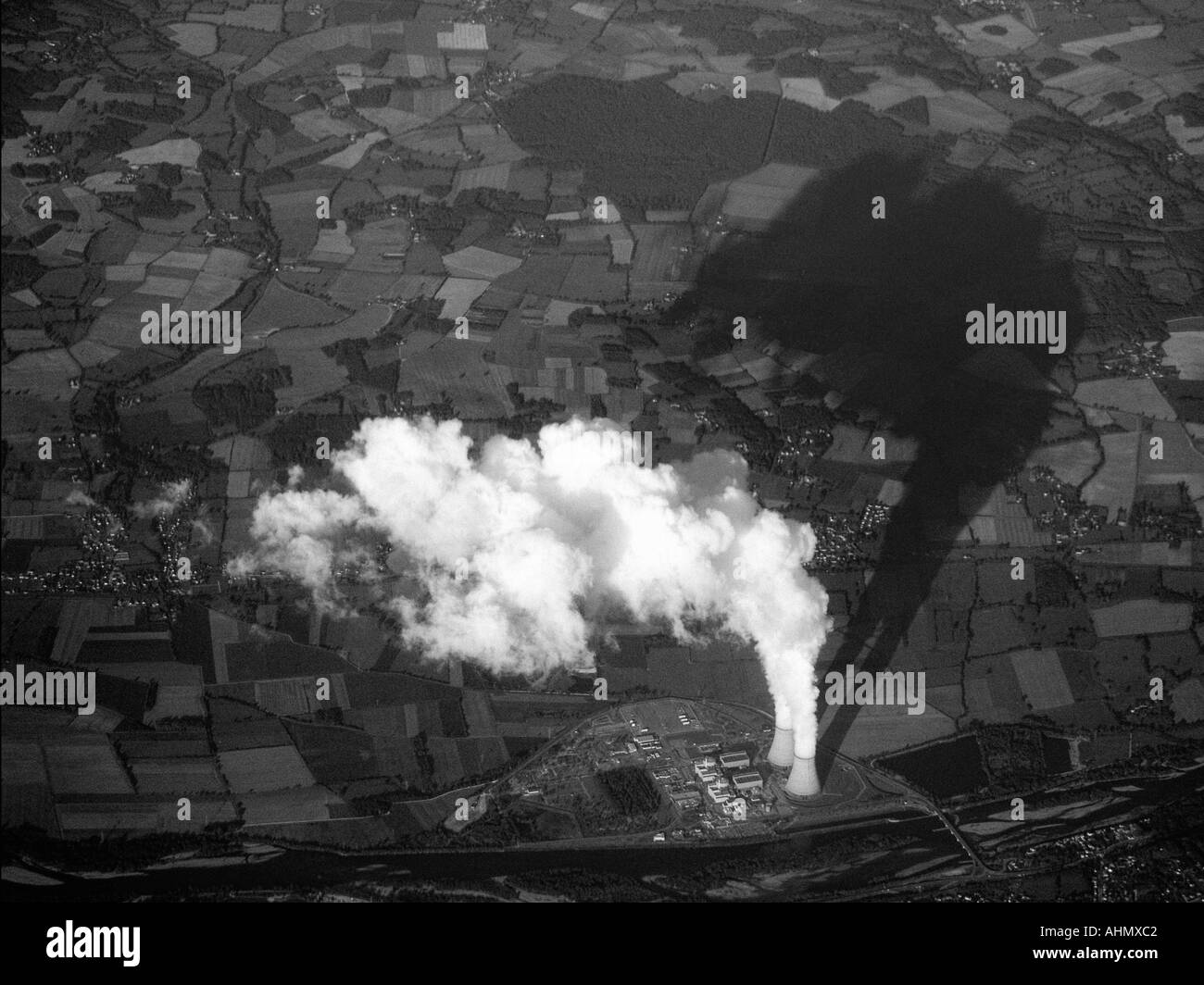 Una torre di raffreddamento proietta una grande ombra minacciosa attraverso la terra Foto Stock