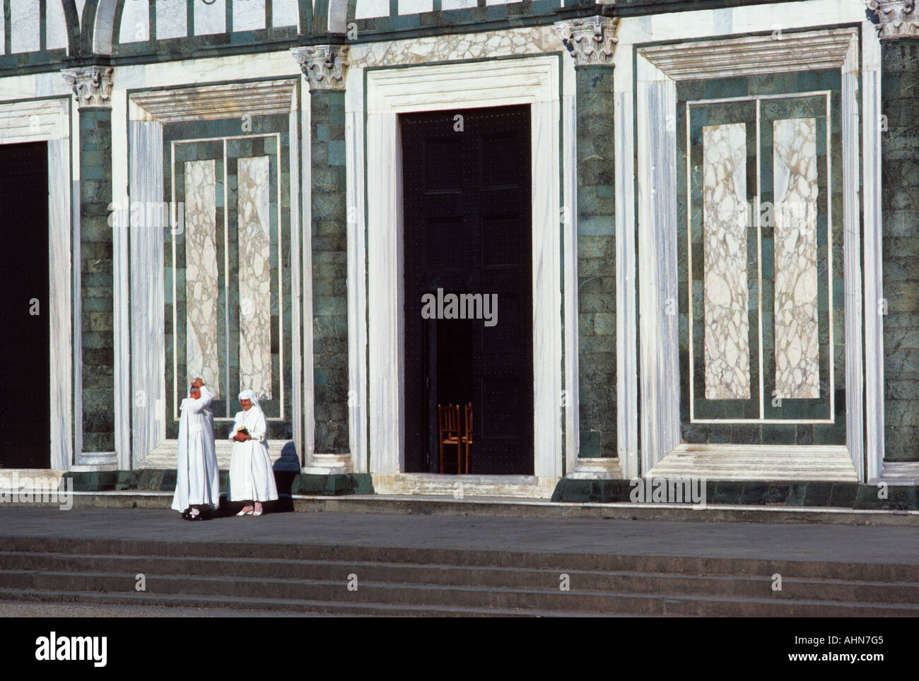 Chiesa di San Minato al Monte in Toscana città collinare a Firenze, Italia. Sacerdote e suora che parlano. Facciata in marmo verde e bianco di un edificio romanico Foto Stock