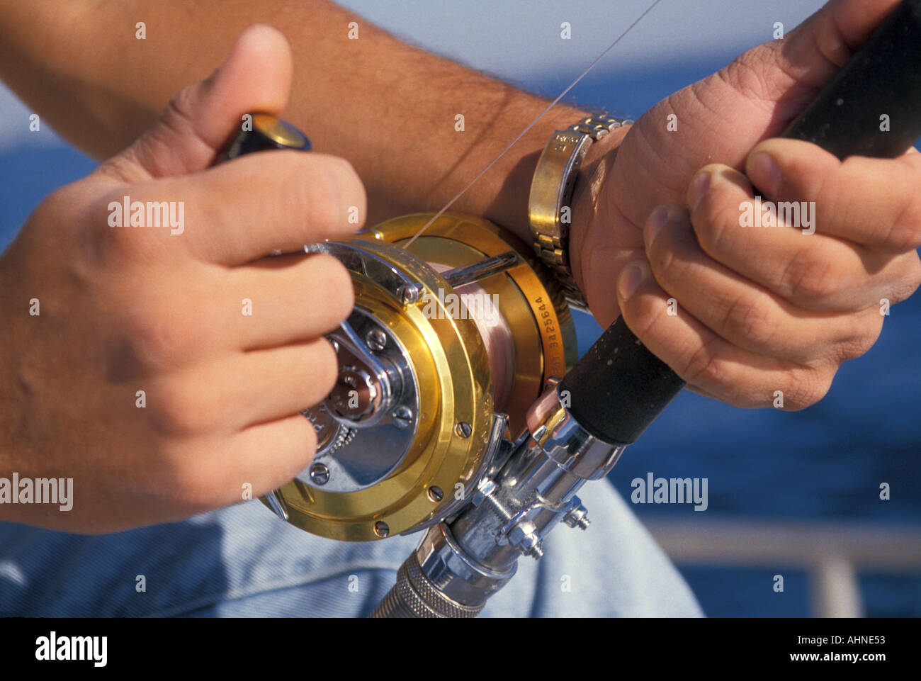 La pesca in mare profondo mare Carta Oro mulinello da pesca in pescatore s mani Foto Stock