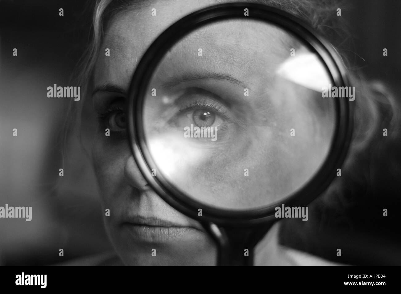 Donna che guarda attraverso la lente di ingrandimento Foto Stock