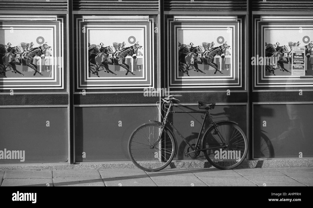 Bicicletta appoggiata contro la parete al di fuori del negozio di bookmaker. Foto Stock