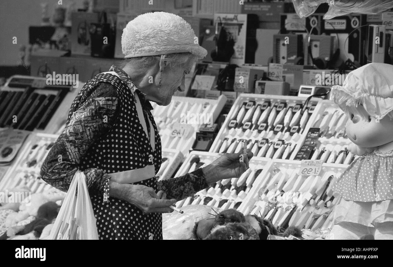 Old Lady con shopping bag guardando gli elementi su un mercato in stallo. Foto Stock