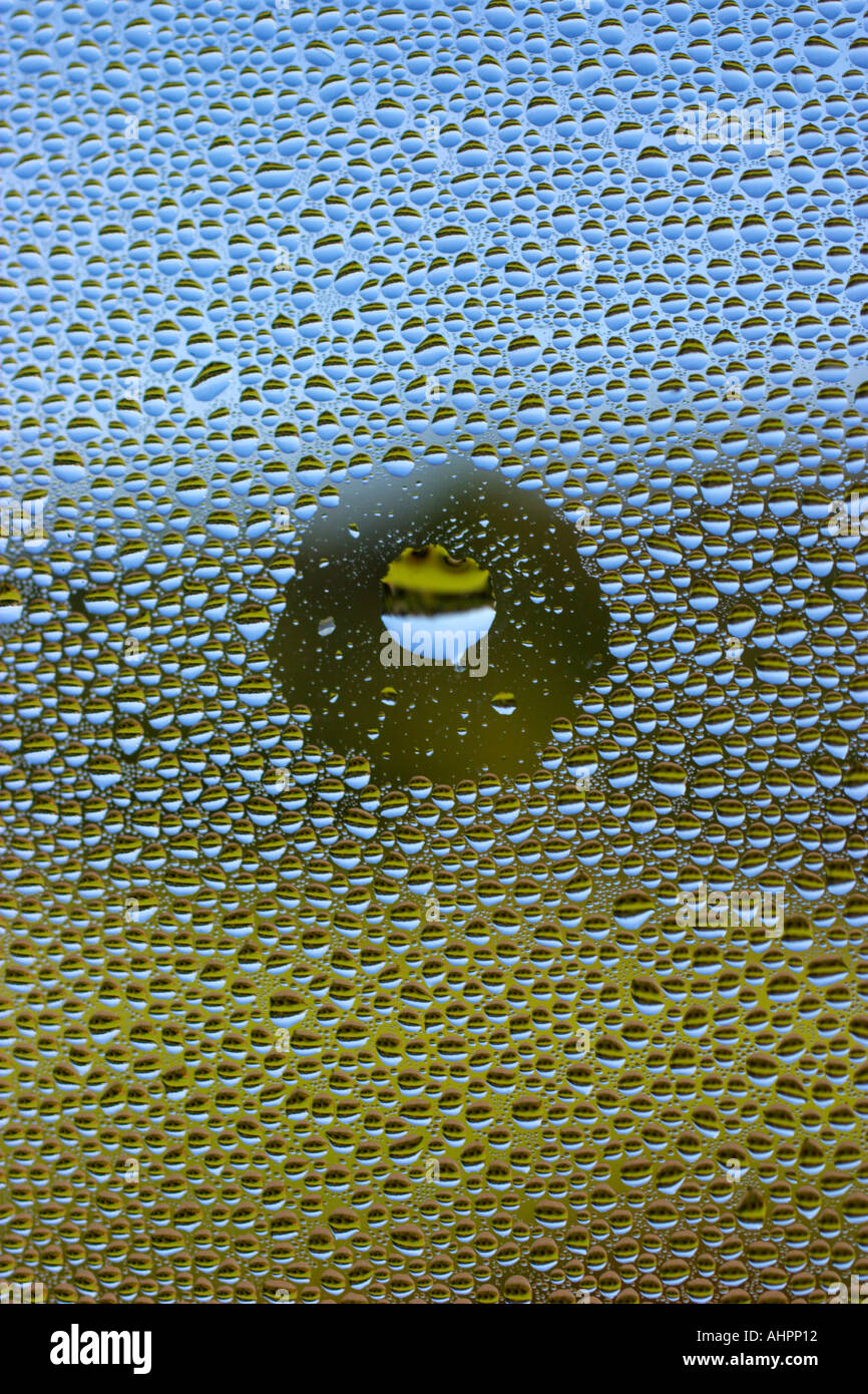 Grandi e piccole di acqua con una vista osservata attraverso una goccia di acqua su vetro Foto Stock