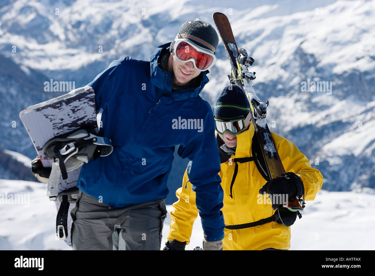 Maschio di sciatore e snowboarder maschio a camminare su crinale il trasporto di sci Foto Stock