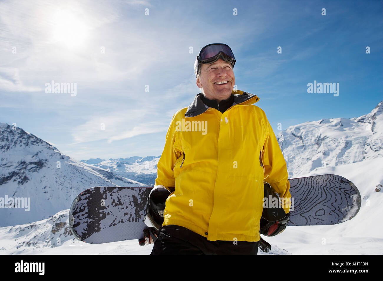Maschio maturo snowboarder con lo snowboard sulla montagna, ritratto Foto Stock