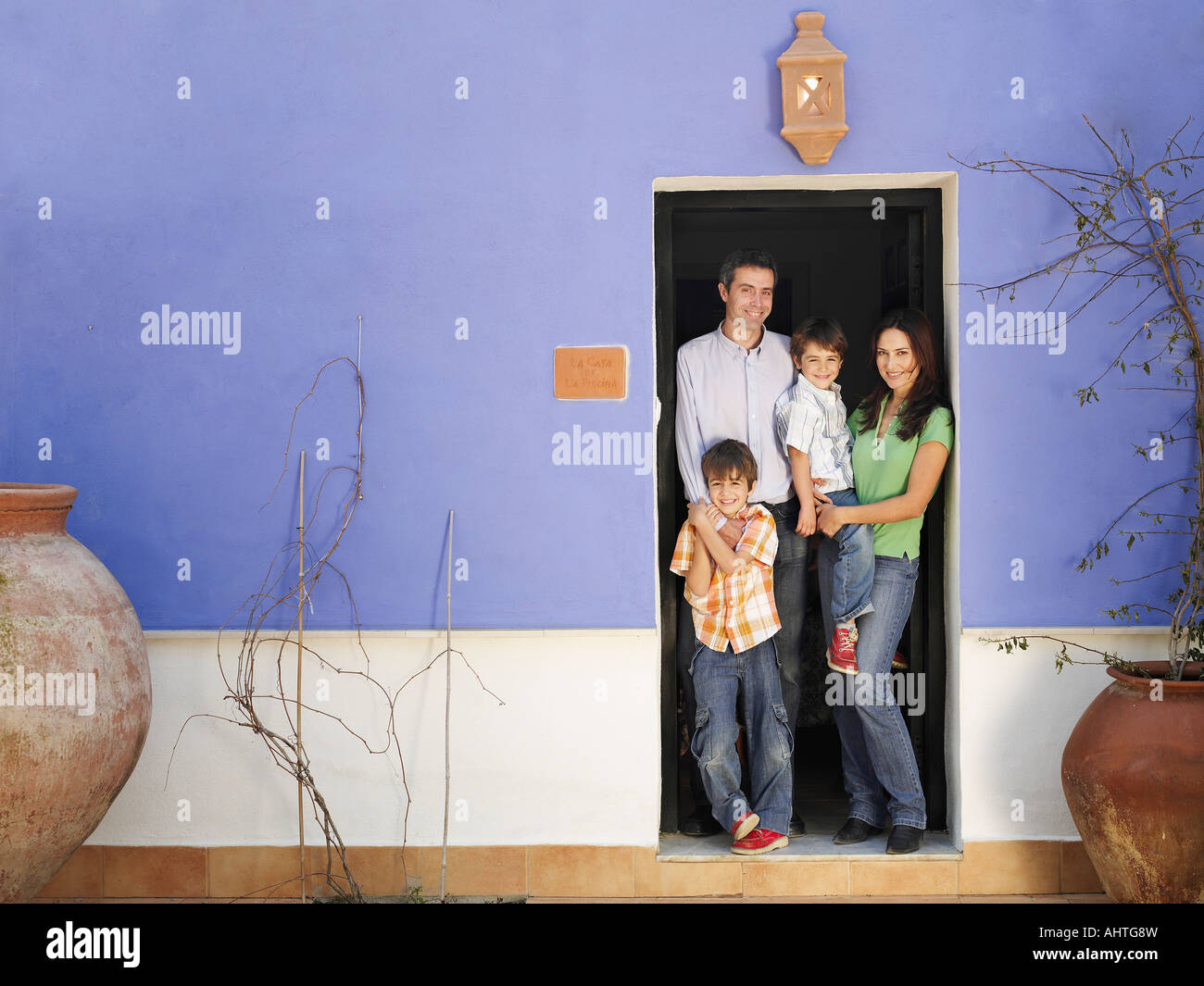 Genitori e figli gemelli (4-6) in piedi in porta, sorridente, ritratto Foto Stock