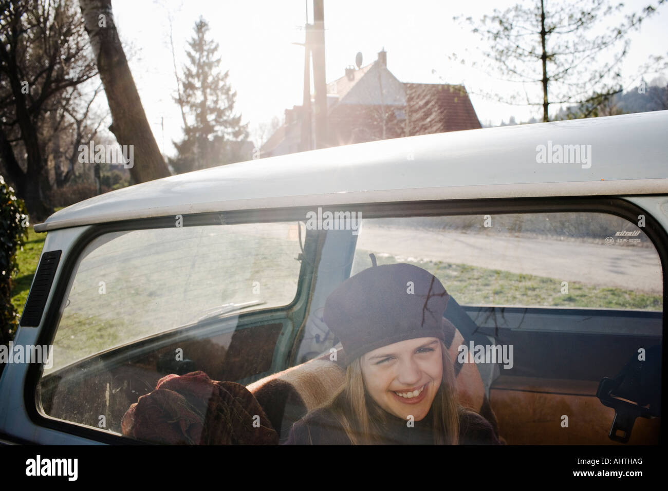 La ragazza (10-12) in seduta posteriore della vettura, sorridente, vista attraverso la finestra Foto Stock