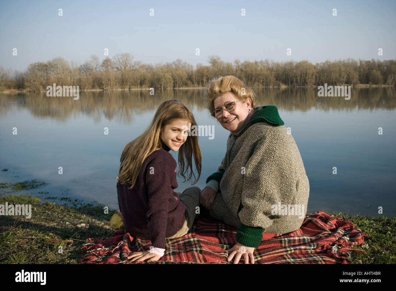 Nonna e nipote (10-12) seduto sul tappeto da fiume, sorridente Foto Stock