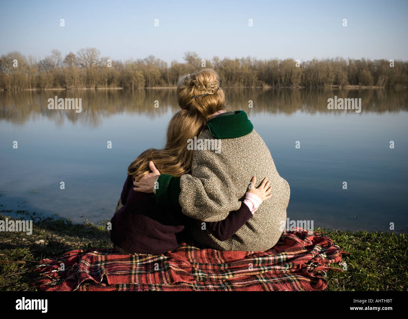 Nonna e nipote (10-12) seduta dal fiume, vista posteriore Foto Stock