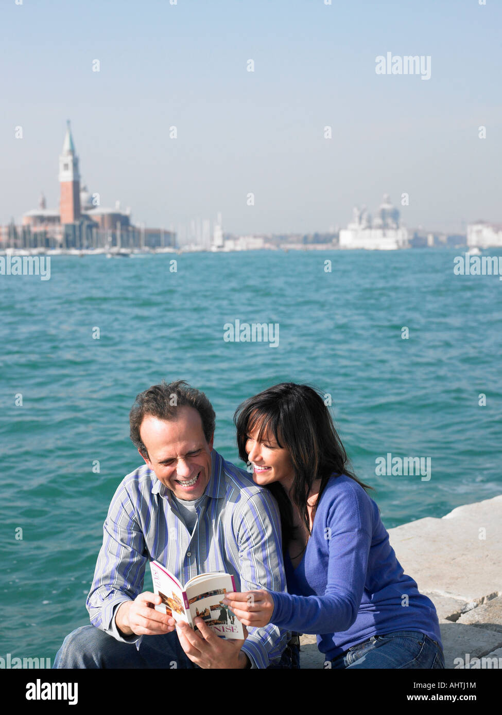 Giovane seduto guardando il libro guida. Venezia, Italia. Foto Stock