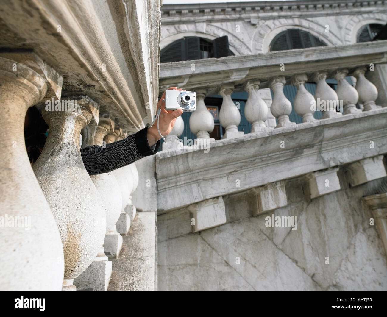 Donna di mano che tiene la fotocamera digitale fotografia presa attraverso il parapetto in pietra del Ponte di Rialto. Venezia, Italia. Foto Stock