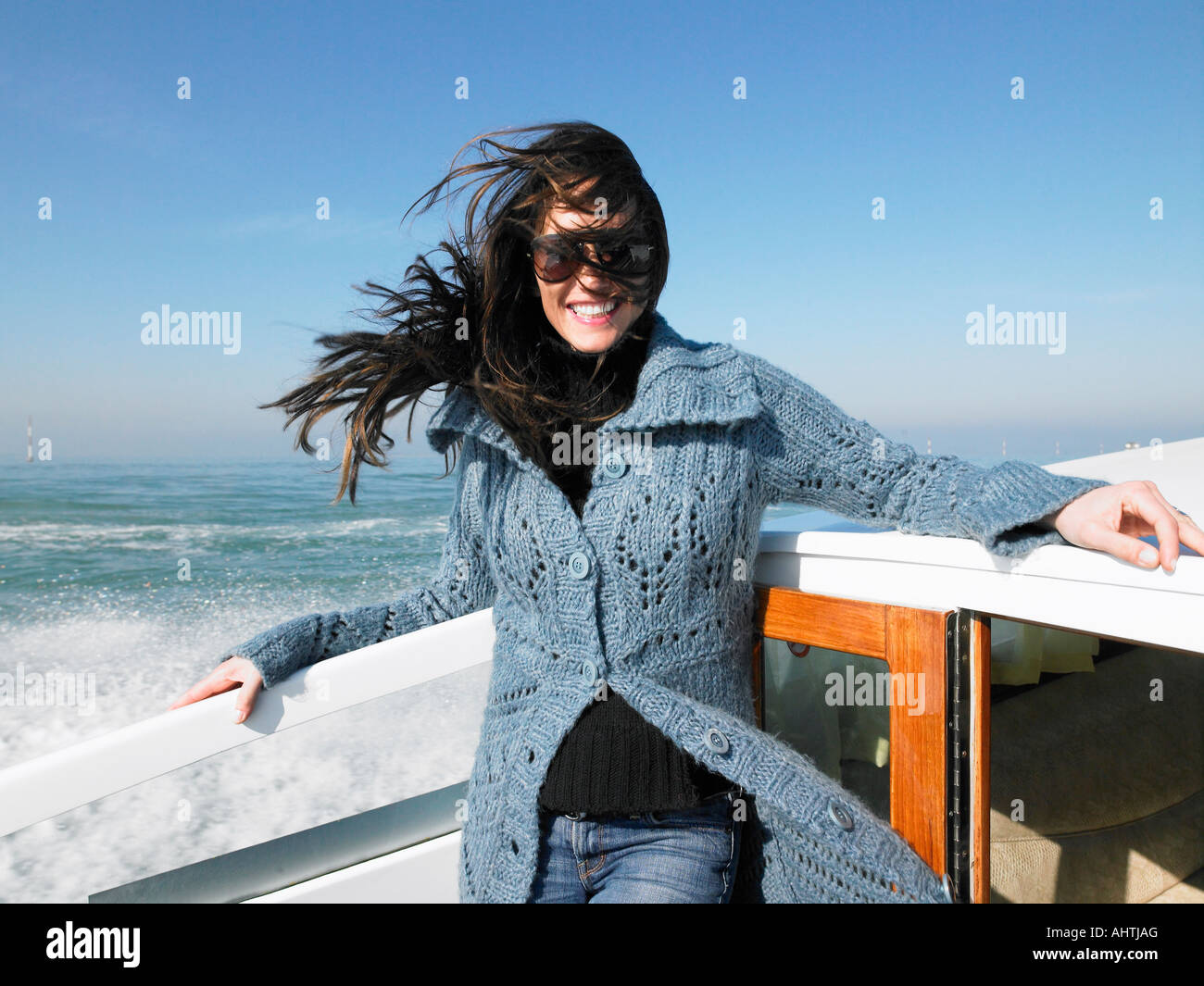 Donna che indossa gli occhiali da sole sul battello, sorridente Foto Stock