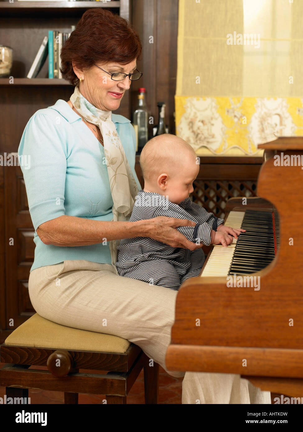 Nonna Senior suonare il pianoforte con baby grandson (1-3 mesi) Foto Stock