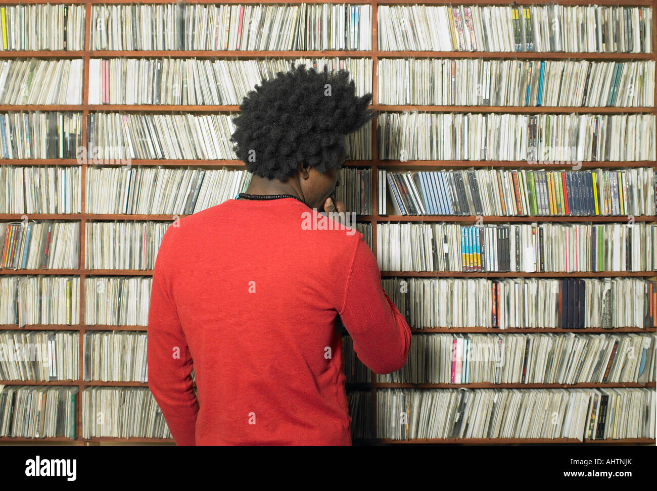 Uomo che guarda un compact disc su scaffali in negozio di musica, vista posteriore Foto Stock